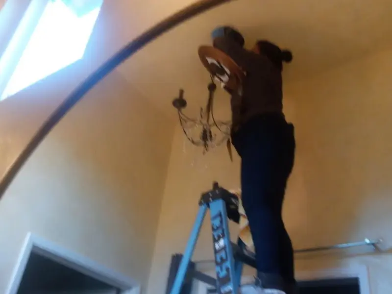 Electrician installing a chandelier in a Reynolds residence